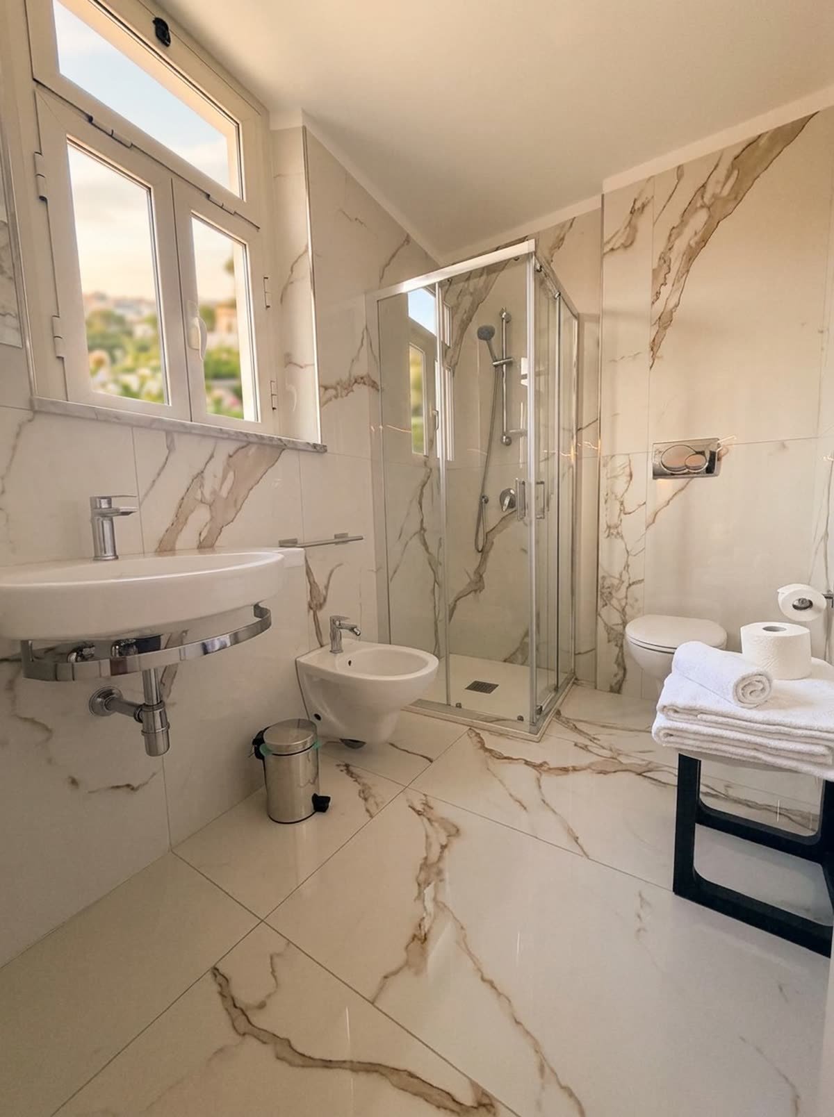 Al Pozzo — il bagno in marmo con doccia e finestra sul verde