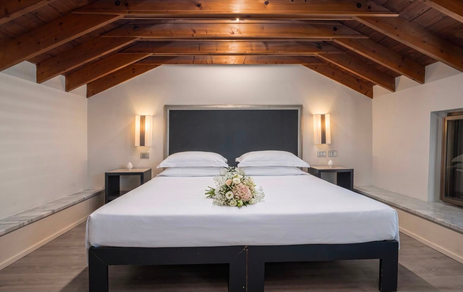 Ai Faraglioni — letto matrimoniale nel sottotetto con travi a vista